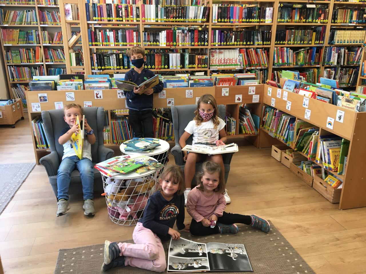 Fünf Kinder die sich Bücher der Bibliothek ansehen