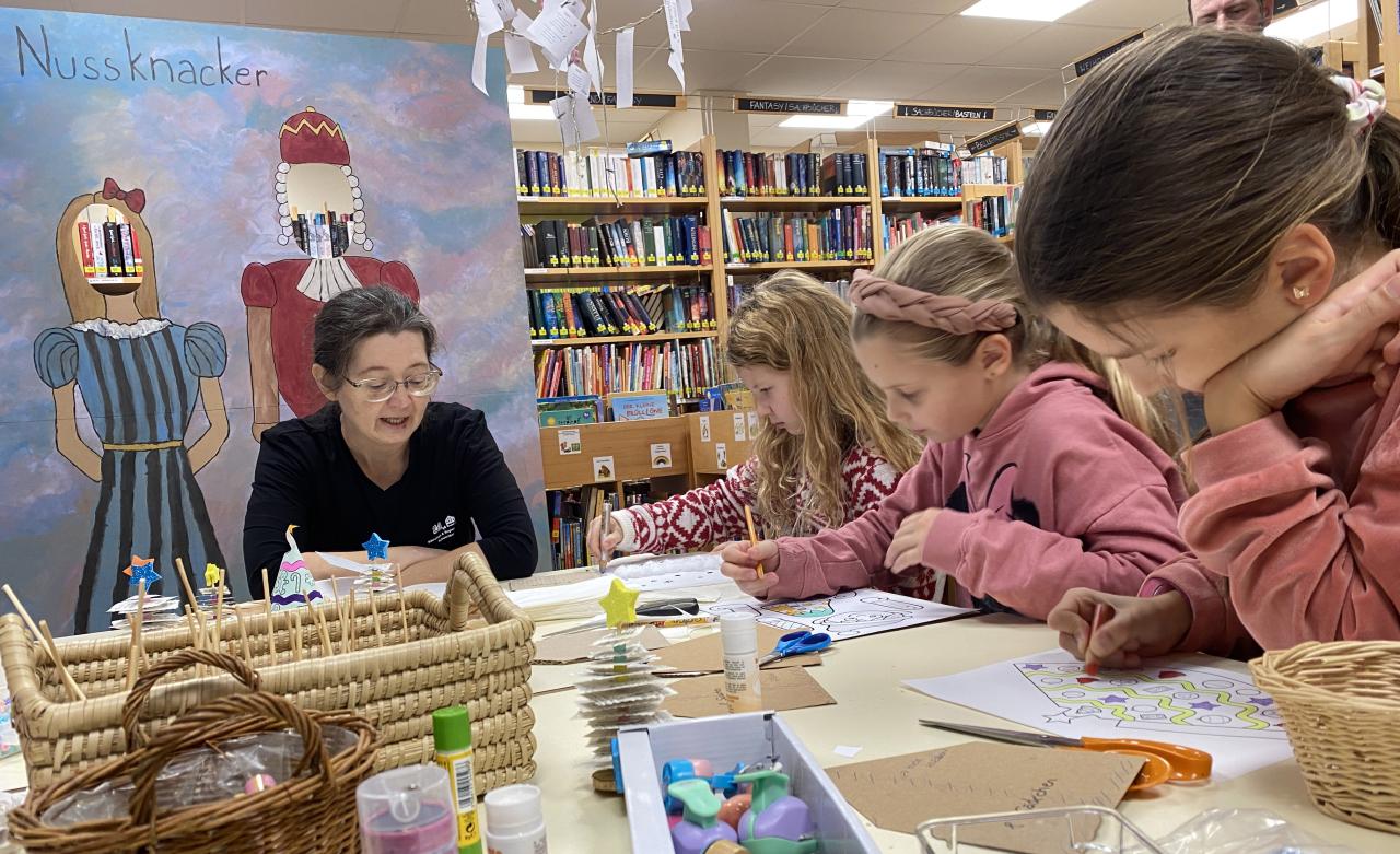 Ein Frau liest drei Kindern aus einem Buch vor