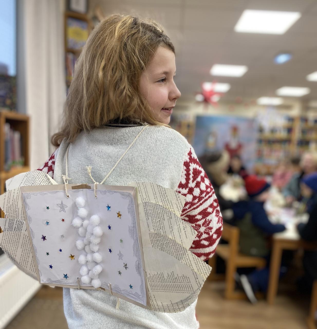Ein Mädchen hat Flügel aus Buchseiten am Rücken