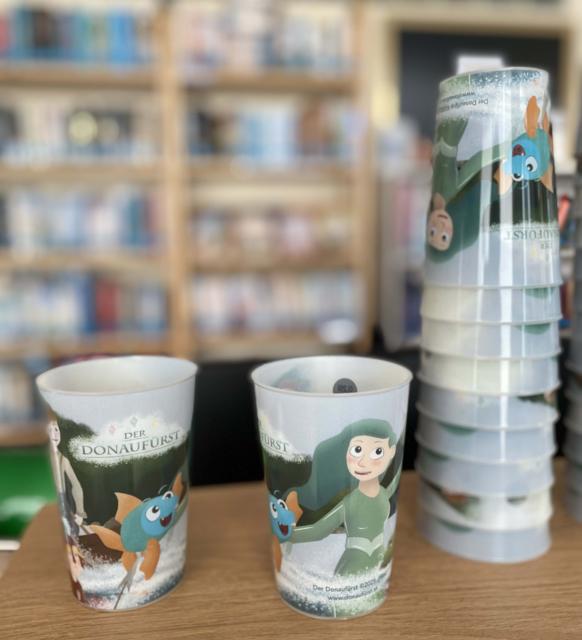 zwei Becher auf denen Bilder des Films gedruckt sind