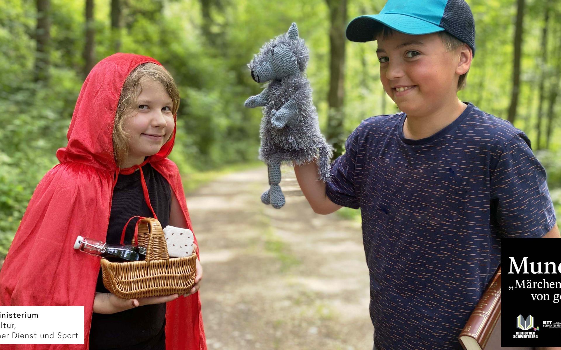 Ein Mädchen mit Rokäppchenumhang und eine Junge mit einer Wolfshandpuppe