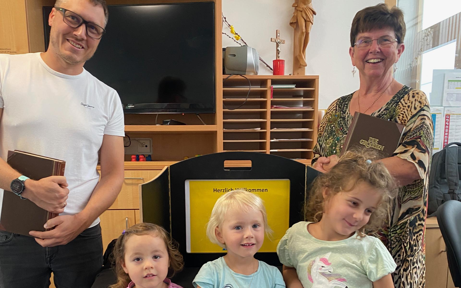 Zwei Erwachsene Vorleser und drei Kinder sind am Bild