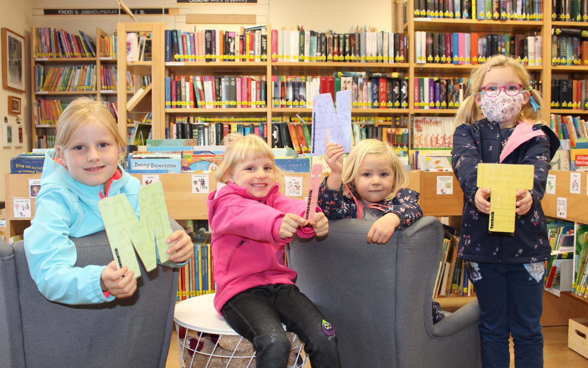 Vier Kinder halten die Buchstaben MINT in der Hand