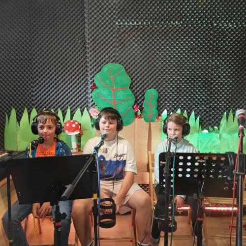 Drei Kinder im Tonstudio vor Mikrofonen